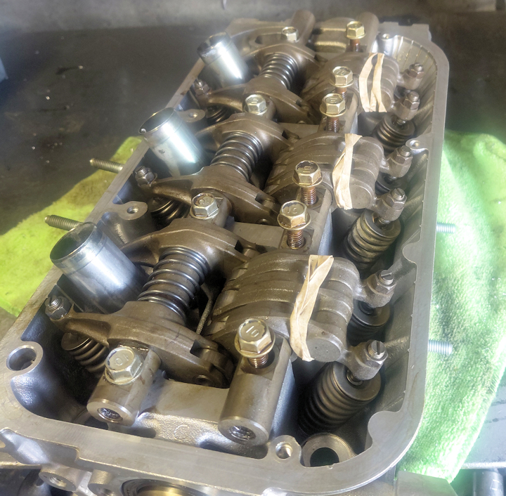 Honda VTEC cylinder head with piston-loaded rocker arms secured by rubber bands during disassembly